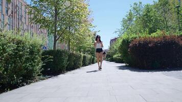 Woman walking on a sunny day in a park with greenery and pathways video