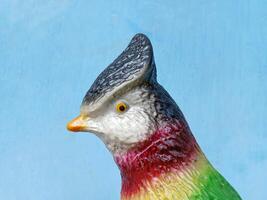 statue of a parrot animal character on a twig on a blue background photo