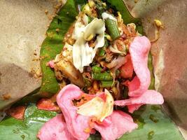 Close up view of Lotek, Indonesian traditional food made from boiled vegetable with peanut sauce served with crackers photo