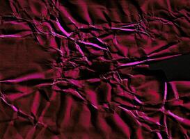 Crumpled paper texture featuring vivid pink highlights and deep black shadows, creating a striking abstract effect. photo