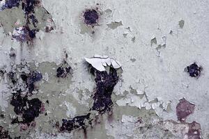 Close-up of peeling paint on a weathered surface with dark stains, ideal for grunge backgrounds and creative design. photo