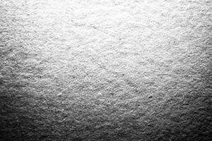 A monochrome close-up of textured paper with soft grain and light gradient, ideal for background and design projects. photo