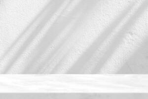 Marble Table with White Stucco Wall Texture Background with Light Beam and Shadow photo