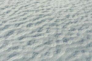 Texture of snow. Melted snow in winter in sun. Surface is wavy. photo
