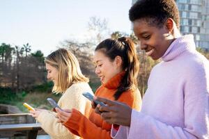 Cheerful female friends using cell phones. Technology addicted concept photo