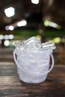 Ice cube in a transparent plastic bucket on a table photo
