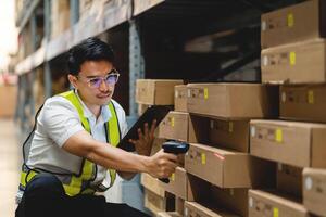 A man in a yellow vest is scanning a barcode on a box. He is wearing glasses and is looking at the box photo
