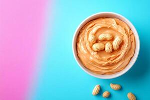 Creamy peanut butter in bowl with peanuts on colorful background photo