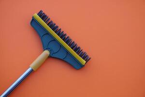 Brush for cleaning floor on orange background. Concept, tool for cleaning. use for scrub dirty on bathroom floor. photo