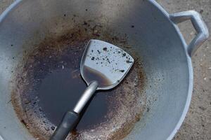 Close up cooked oil in a ladle with burnt stain of fried food scrape in pan. Concept, unhealthy cooking. Oil used for frying food should not be reused because it contains carcinogens. Health care. photo