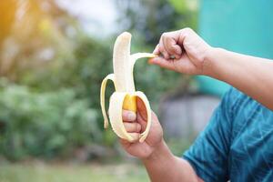 Close up hands are peeling banana to eat. Concept, nourishment and relieve hunger by eating banana, Benefit to health with food nutrition value. Healthy lifestyle. Enjoy eating fruits. photo