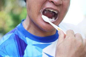 Close up man is brushing his teeth. Concept, dental health care. Brush teeth with fluoride toothpaste for hygiene, clean and strong teeth. Prevention from tooth decay. photo