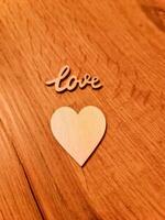 A sweet romantic heart with the word Love lies on a rustic wooden surface. photo