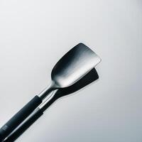 Close-up of a sleek stainless steel spatula with a black handle, reflecting on a smooth surface. photo
