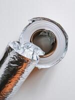 Close-up of a roll of aluminum foil with partially unwrapped layers, showcasing its shiny surface. photo