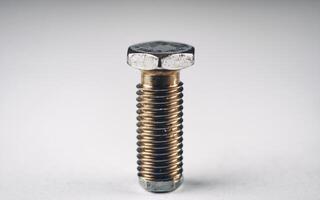Close-up of a metallic bolt against a plain background, showcasing its detailed texture and structure. photo