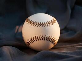 A close-up of a white baseball resting on a dark, textured surface. photo