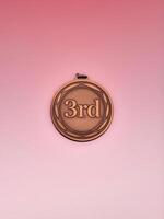 Bronze medal displaying '3rd' on a soft pink background, symbolizing achievement and success. photo