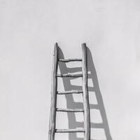 A rustic wooden ladder leaning against a white wall, casting a soft shadow, creating a serene atmosphere. photo