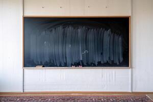 A clean black chalkboard in a bright classroom setting, ready for new lessons. photo