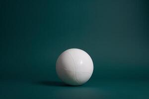 Minimalistic view of a white volleyball on a dark green background, highlighting its texture and shape. photo