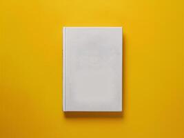 A blank white book placed on a vibrant yellow background, creating a minimalist aesthetic. photo