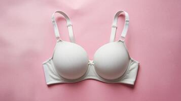 Elegant white bra laid on a soft pink background, highlighting its smooth design and supportive structure. photo