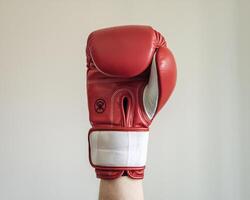 A close-up of a red boxing glove held high, symbolizing strength and determination. photo