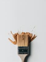 A dynamic splash of brown paint erupts from a clean paintbrush against a soft blue background. photo