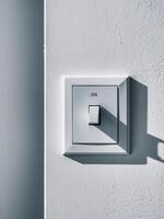 Close-up of a modern light switch turned on against a textured wall. photo