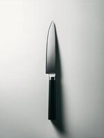 A sleek, metallic kitchen knife with a black handle, expertly illuminated against a minimalist backdrop. photo