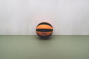 An orange and black basketball resting on a green surface against a plain background. photo
