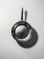 A reflective stainless steel frying pan cast in soft light, showcasing its sleek design and subtle scratches. photo