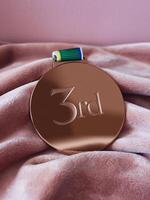Bronze medal rests on soft fabric, symbolizing achievement and success in competition. photo