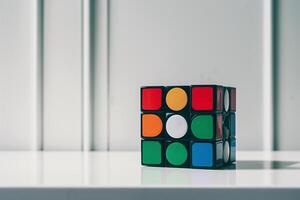 A colorful Rubik's Cube on a sleek white surface, showcasing its vibrant colors and geometric patterns. photo