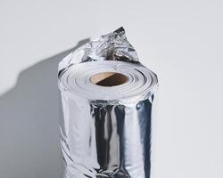 A rolled-up aluminum foil with a shiny metallic finish against a minimalistic backdrop. photo