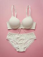 Elegant white lingerie set on pastel pink background, featuring a soft cup bra and matching panties. photo