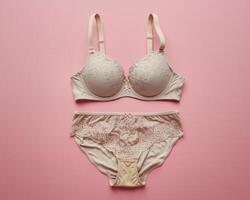 Elegant beige lace lingerie set laid out on a soft pink background, perfect for a feminine touch. photo