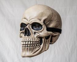A realistic male skull mask, showcasing intricate details and lifelike features against a neutral background. photo