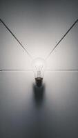 A glowing light bulb casts a warm glow against a minimalistic white background. photo