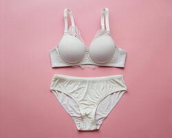 Elegant white lace bra and matching panties on a soft pink background. photo