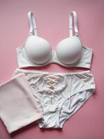 Elegant white lingerie set displayed on a soft pink background, perfect for a romantic mood. photo