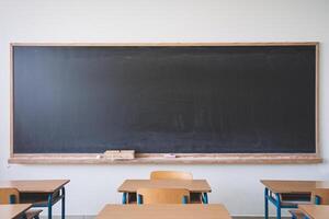 Empty classroom with wooden desks and a clean blackboard, ready for lessons. photo