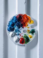 A vibrant artist's palette displaying an array of colorful paints on a white wooden background. photo