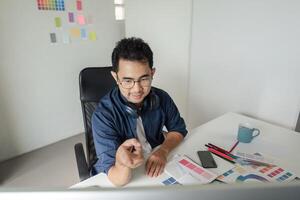 Creative Graphic Designer Working in Modern Design Studio with Color Swatches and Digital Tools for Innovative Projects photo
