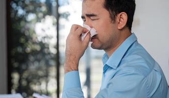 Office Worker Feeling Unwell with Cold Symptoms at Desk in Modern Workplace Environment photo