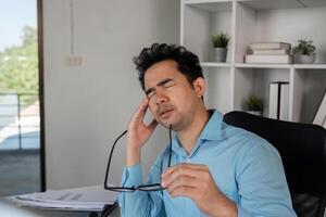 Exhausted Office Worker Experiencing Headache from Intense Workload in Modern Workplace Setting photo