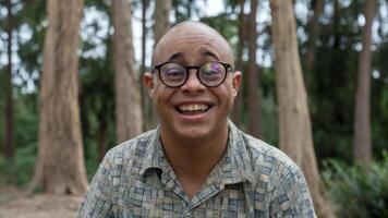 Photo of bald man with Down syndrome smiling warmly, conveying joy and positivity. Portrait concept