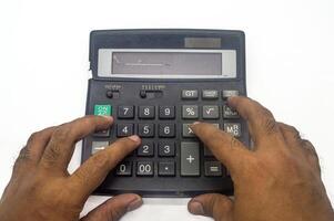 Hands using a large calculator with a broken display on a white background, highlighting the concept of manual calculations and outdated technology photo