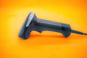 A close up of a handheld barcode scanner on an orange background, showcasing its ergonomic design and functionality. Perfect for retail, inventory, and point of sale applications photo